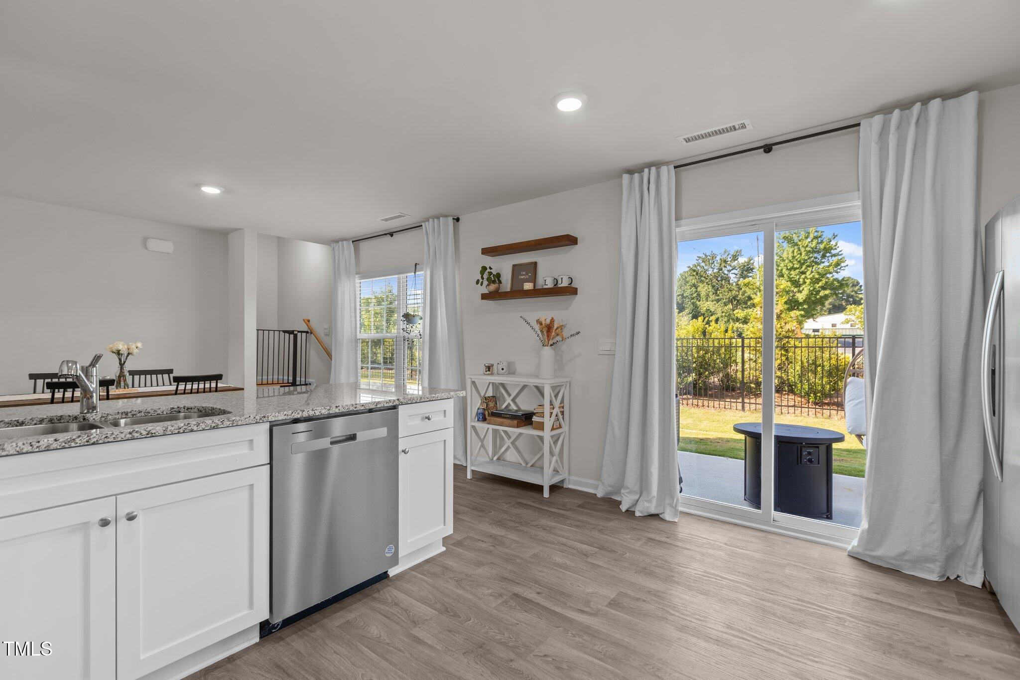 3641 Drafton Drive Raleigh, NC 27610 - Photo 4 of 10 a kitchen with a stove a sink and white cabinets with wooden floor next to windows