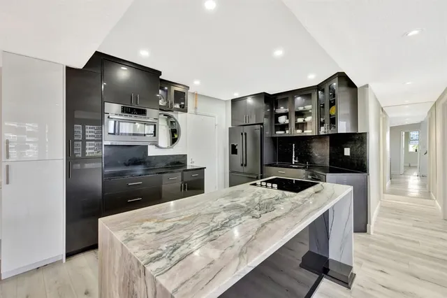 a kitchen with kitchen island stainless steel appliances a sink cabinets and wooden floor