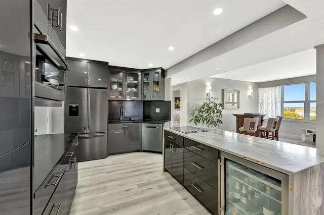 a kitchen with stainless steel appliances kitchen island granite countertop a sink refrigerator and cabinets