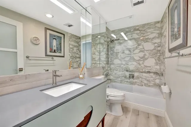 a bathroom with a sink a toilet a mirror a vanity and shower