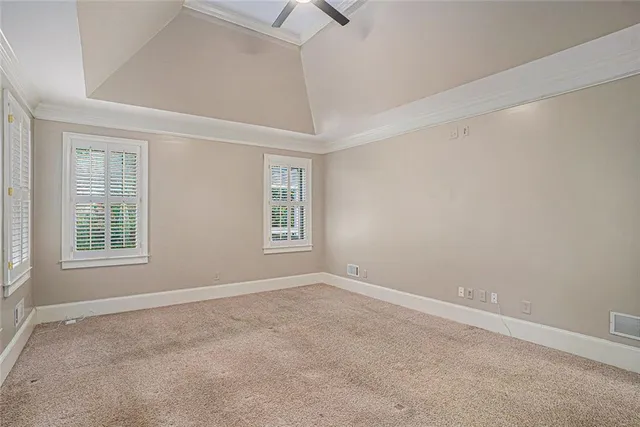 an empty room with a windows and chandelier fan