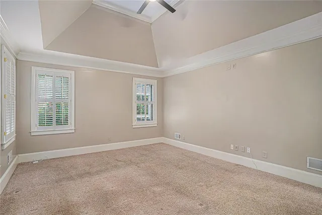 an empty room with a windows and chandelier fan