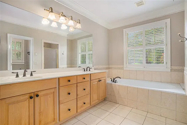 a spacious bathroom with a double vanity sink a large mirror and a bathtub