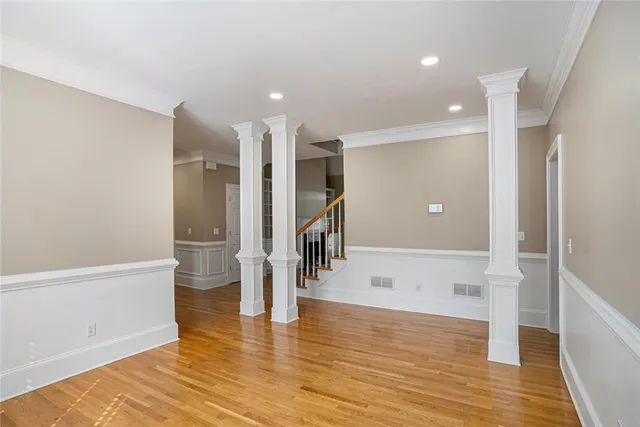 a view of empty room with wooden floor and staircase