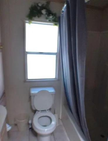 a white toilet sitting in a bathroom next to a window