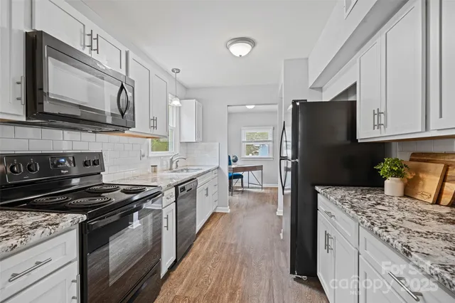 a kitchen with stainless steel appliances granite countertop a stove top oven a sink dishwasher and a refrigerator with wooden floor