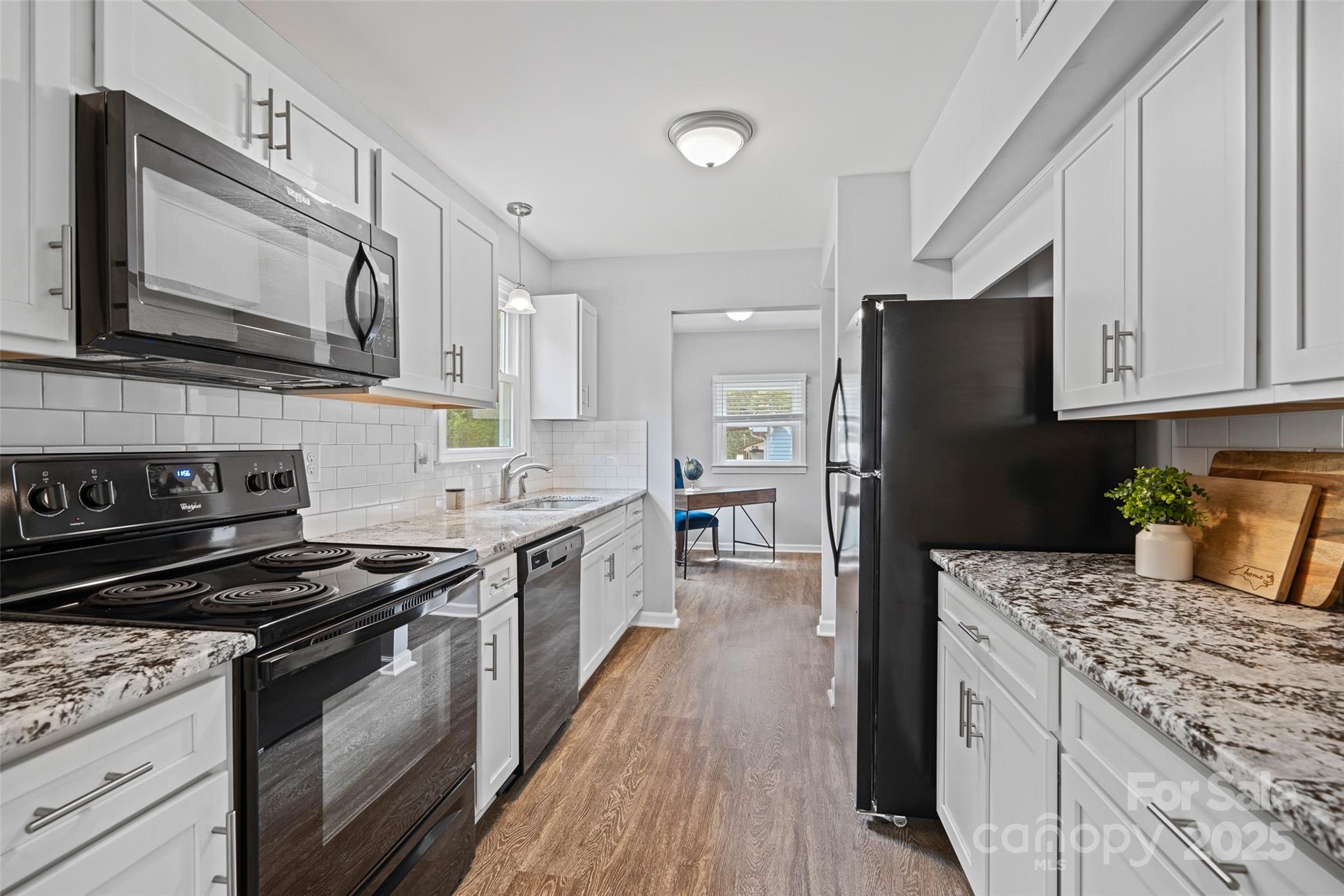 8012 Red Lantern Road Indian Trail, NC 28079 - Photo 3 of 33 a kitchen with stainless steel appliances granite countertop a stove top oven a sink dishwasher and a refrigerator with wooden floor