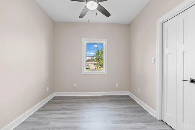 an empty room with a window and a ceiling fan