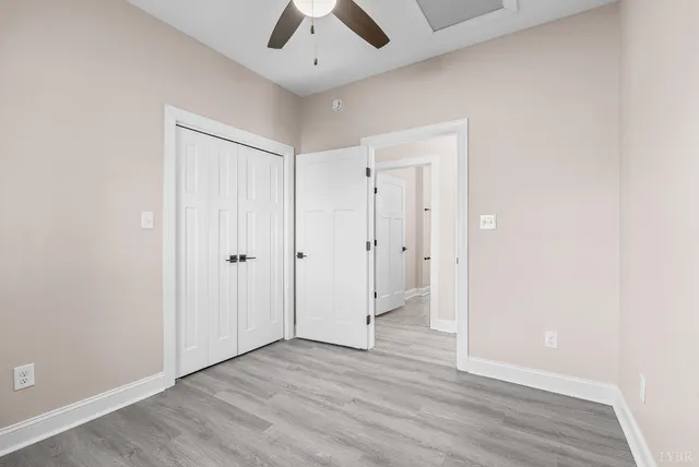 an empty room with wooden floor and ceiling fan