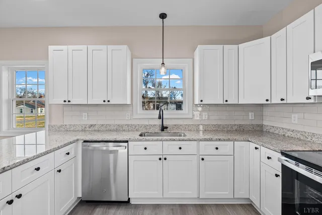 a kitchen with granite countertop white cabinets white appliances and a sink