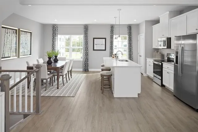 a living room with stainless steel appliances granite countertop furniture wooden floor and a kitchen view