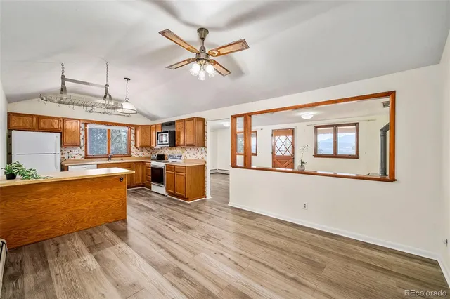 a living room with couches and kitchen view with wooden floor