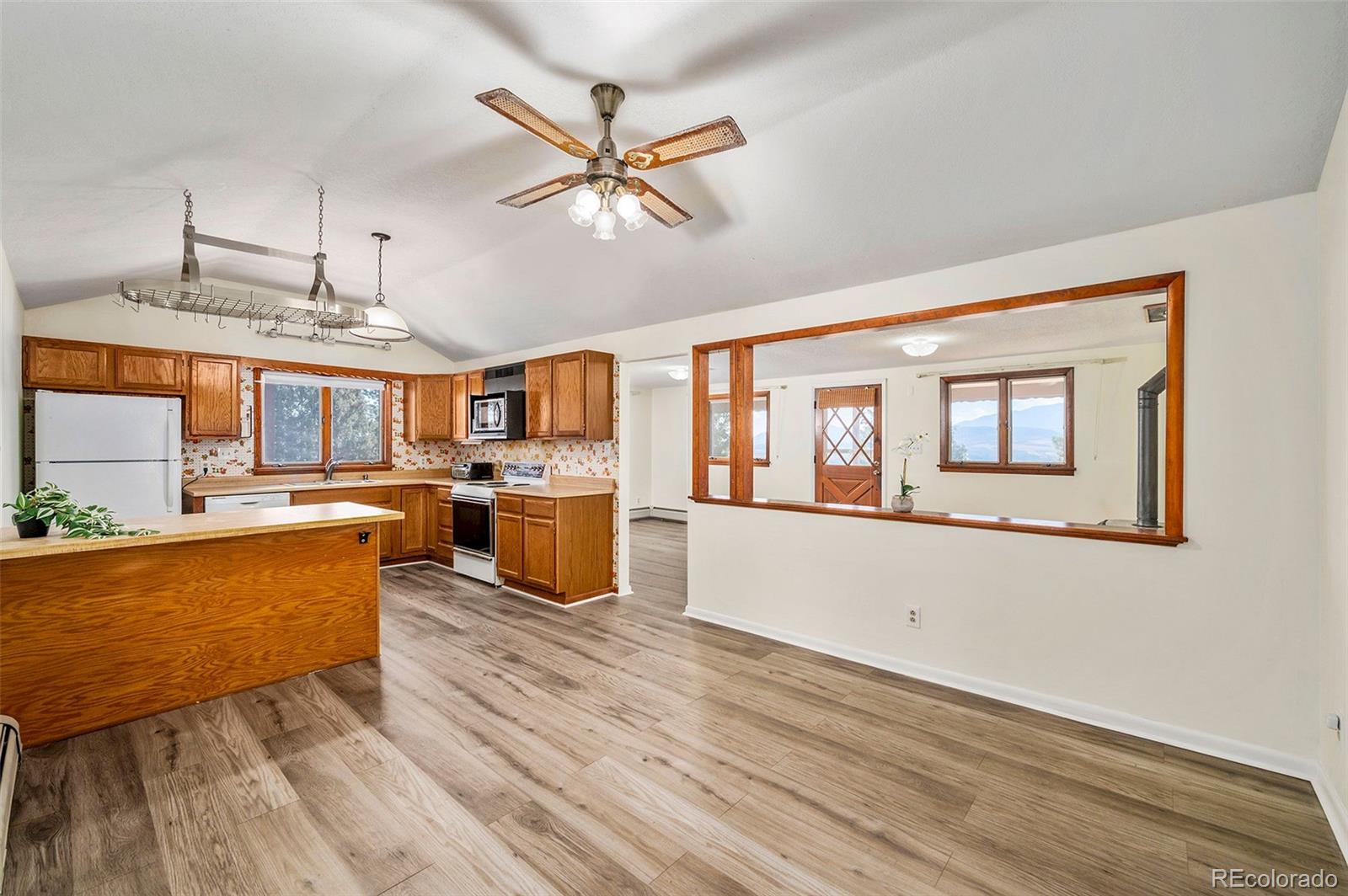 a living room with couches and kitchen view with wooden floor