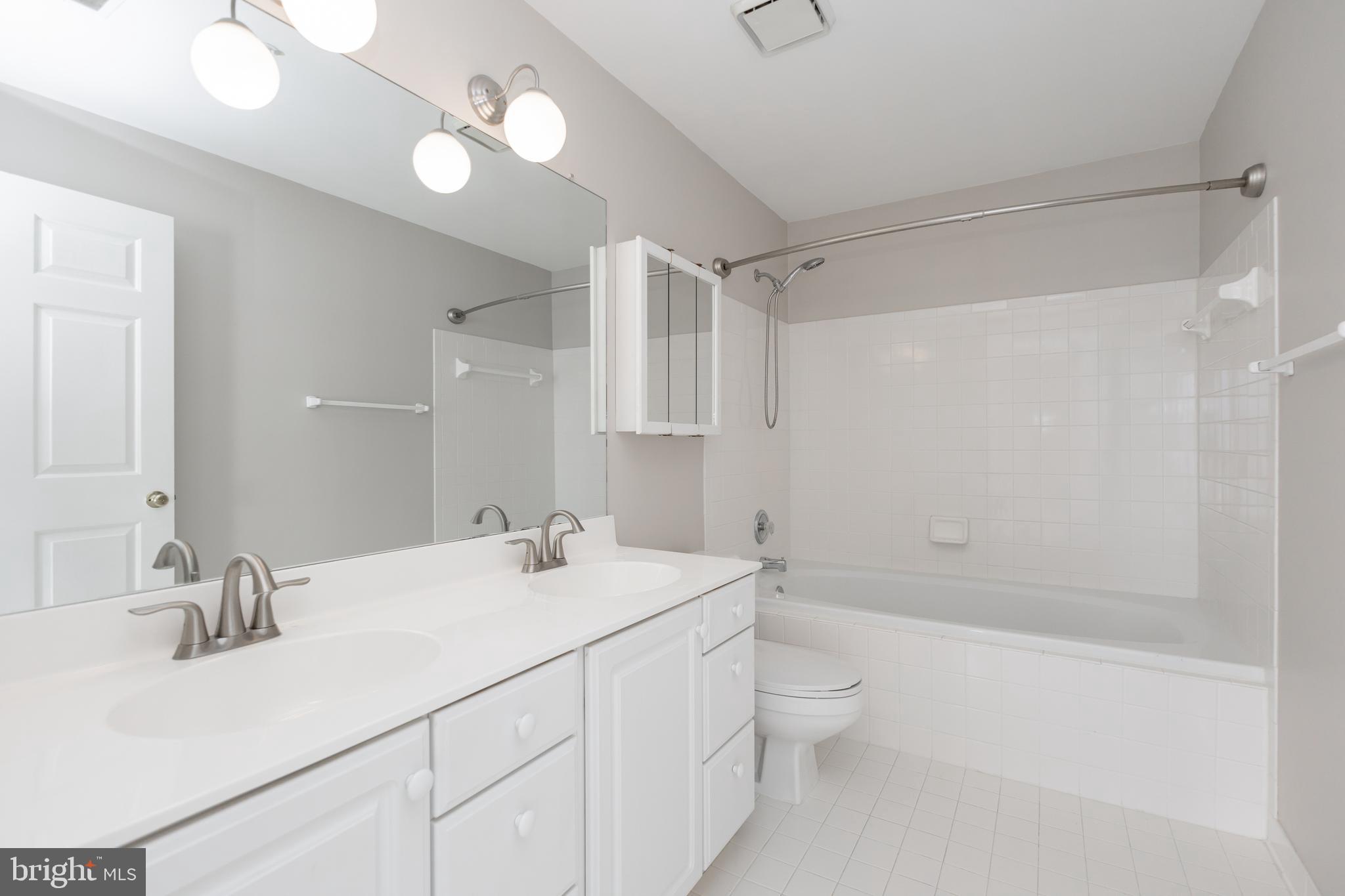 8311 Bluebird Way, Unit K Lorton, VA 22079 - Photo 19 of 25 a bathroom with a double vanity sink toilet mirror and shower