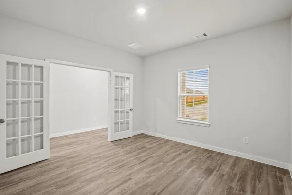 an empty room with wooden floor and windows