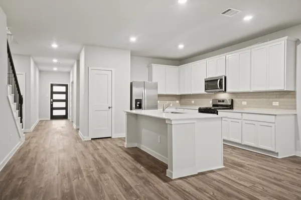 a kitchen with a refrigerator a stove top oven and wooden floor