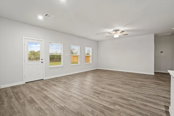 a view of an empty room with a window and wooden floor