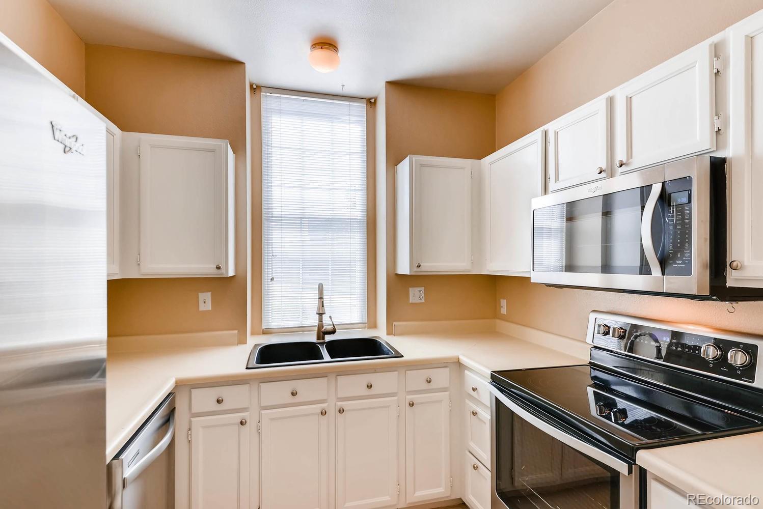 2874 South Genoa Street Aurora, CO 80013 - Photo 8 of 22 a kitchen with stainless steel appliances a sink a stove and a refrigerator
