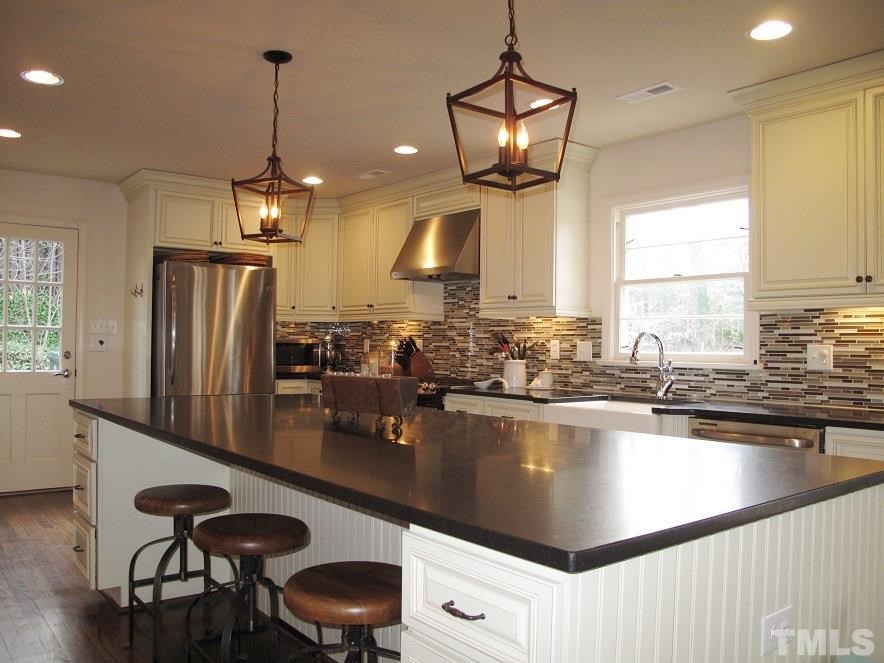 2405 Tyson Street Raleigh, NC 27612 - Photo 7 of 24 a kitchen with stainless steel appliances granite countertop a sink a stove and refrigerator