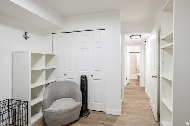 1221 Waterside Cove, Unit 11 Midvale, UT 84047 - Photo 14 of 23 White built-in shelving, light wood-finish flooring, white paneled bifold doors, and a hallway leading to a bathroom with a white tub