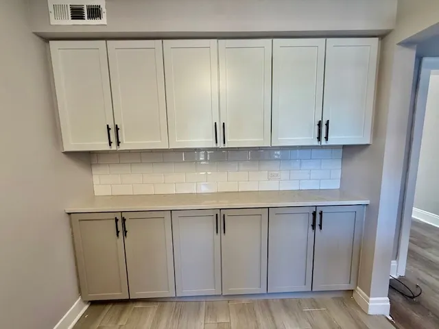 a kitchen with granite countertop white cabinets and wooden floor