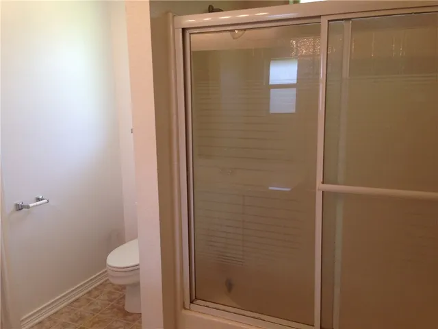 a bathroom with a granite countertop toilet and a shower