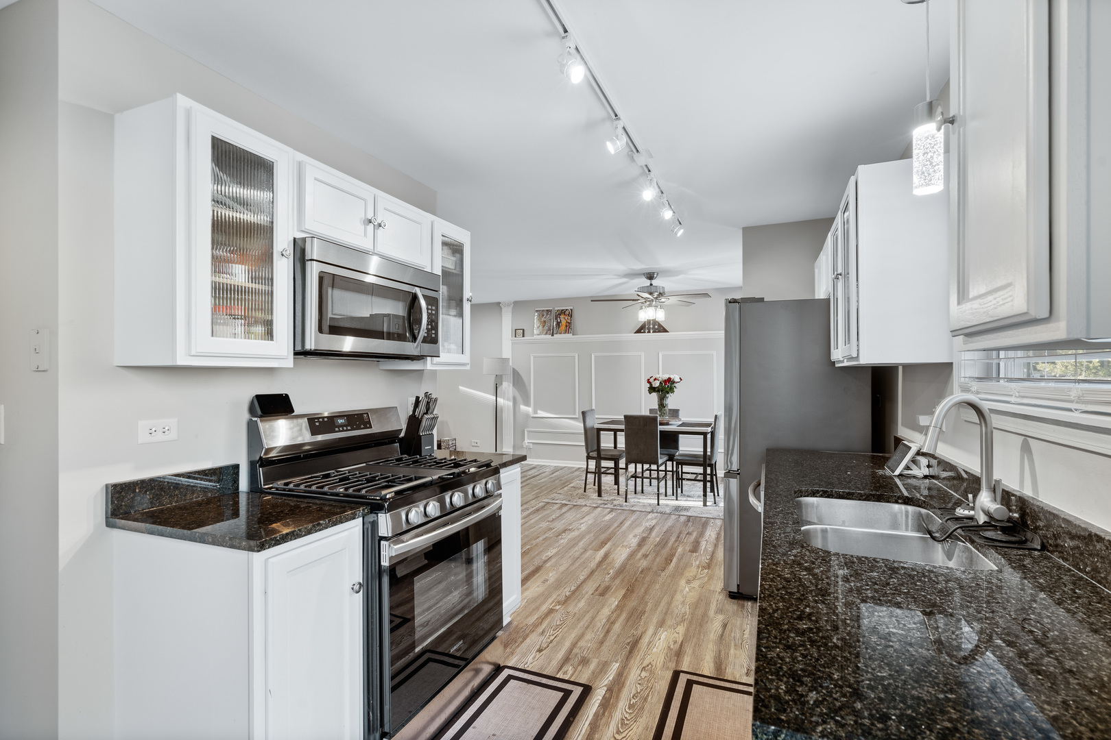 413 Ballard Drive Algonquin, IL 60102 - Photo 7 of 35 a kitchen with stainless steel appliances granite countertop a stove top oven a sink a dining table and chairs with wooden floor