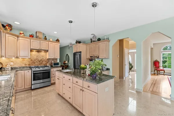 a kitchen with stainless steel appliances kitchen island granite countertop a stove and white cabinets