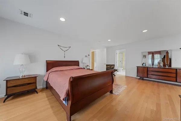 a spacious bedroom with a bed and a lamp with wooden floor