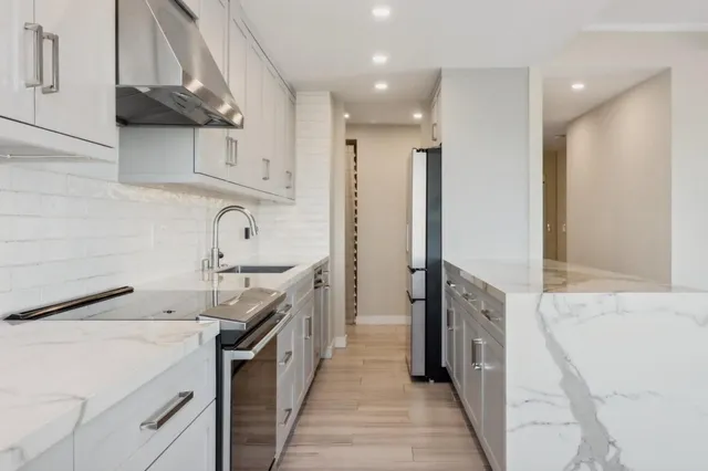 a kitchen with stainless steel appliances kitchen island granite countertop a sink a stove and a refrigerator