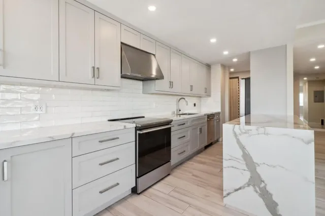 a kitchen with stainless steel appliances granite countertop a sink a stove and a wooden floors