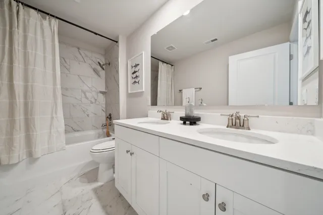 a bathroom with a double vanity sink toilet and shower
