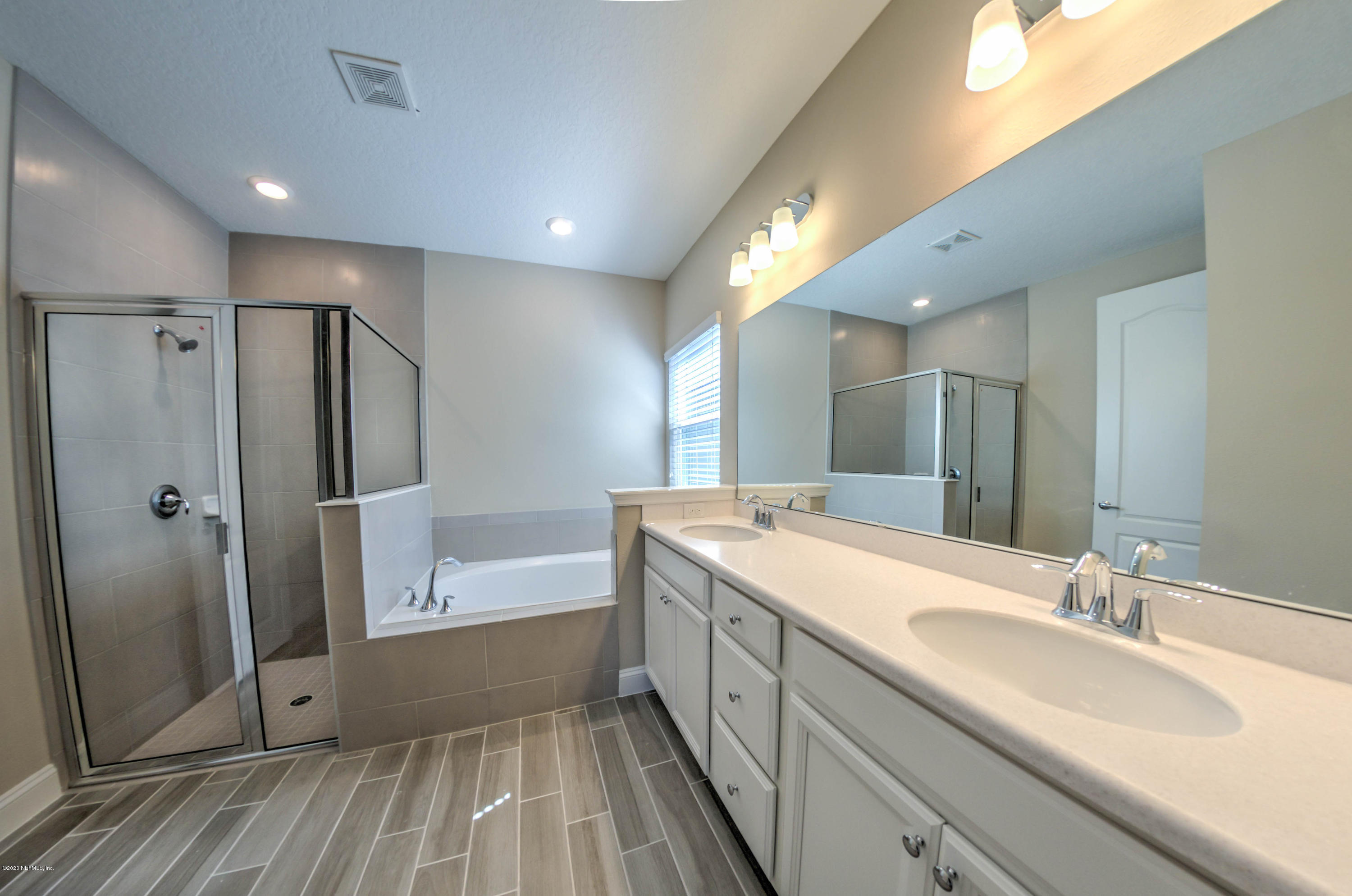 75 Dade Court St. Augustine, FL 32092 - Photo 11 of 25 a bathroom with a double vanity sink a mirror and a bathtub