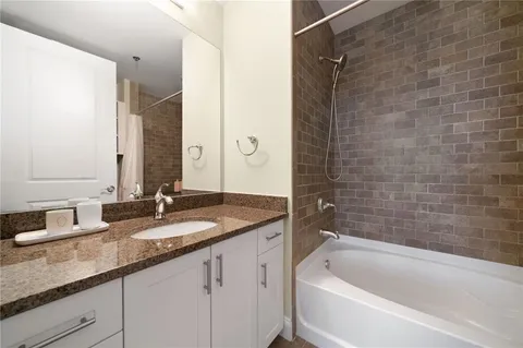 a bathroom with a granite countertop bathtub sink vanity and mirror
