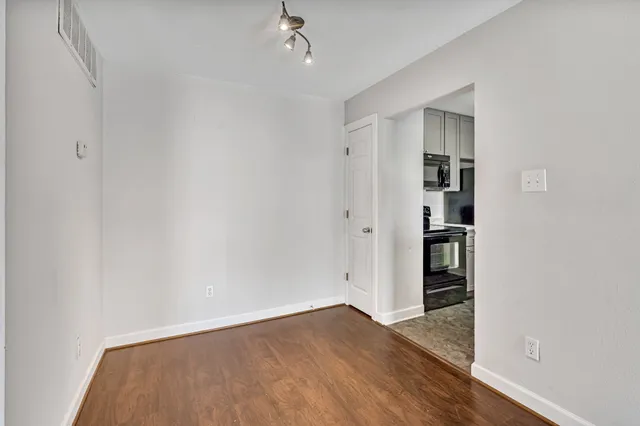 an empty room with wooden floor closet and windows