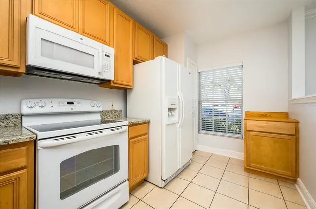 a kitchen with granite countertop a stove top oven microwave and refrigerator