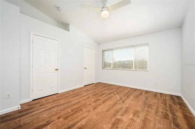 a view of empty room with wooden floor and fan
