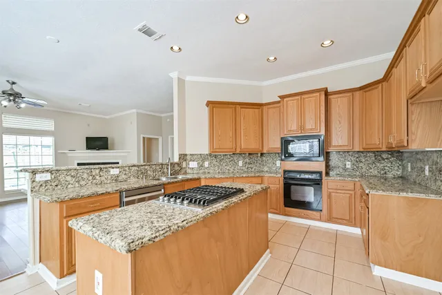 a kitchen with kitchen island granite countertop a sink stove and cabinets