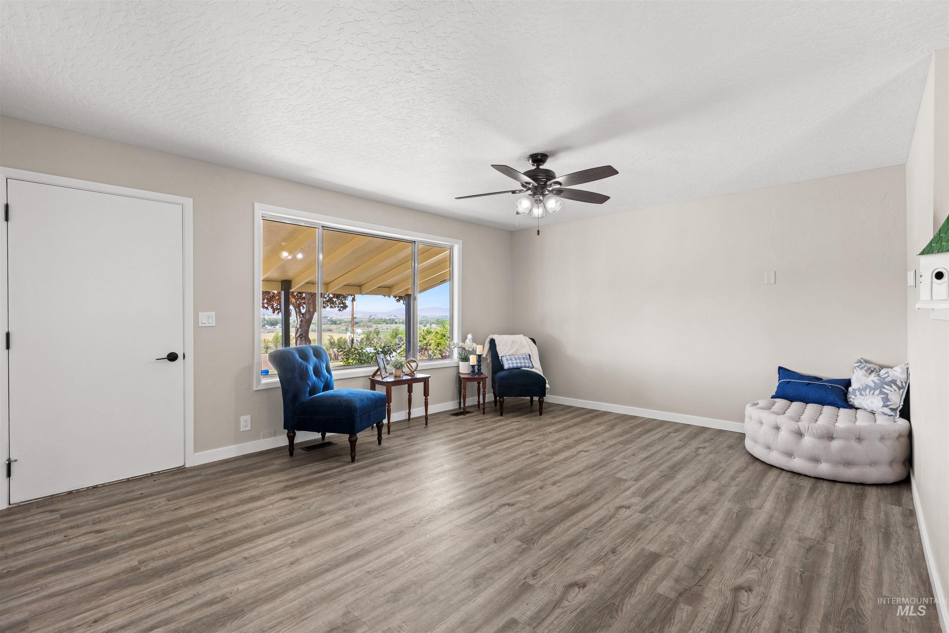 12184 Hill Road Payette, ID 83661 - Photo 9 of 35 Spacious living area featuring wood-finish flooring, neutral wall tones, and a ceiling fan with integrated lighting