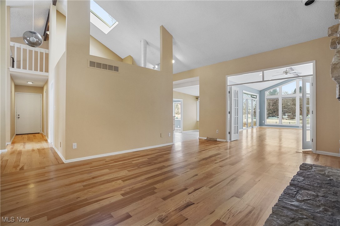 1094 San Raphael Drive Akron, OH 44333 - Photo 26 of 50 Unfurnished living room featuring high vaulted ceiling, light wood-style floors, a skylight, and ceiling fan
