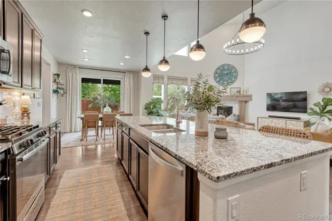a kitchen with granite countertop stainless steel appliances a stove center island a oven a dining table and chairs