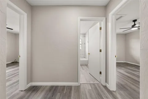 a view of empty room with wooden floor and fan