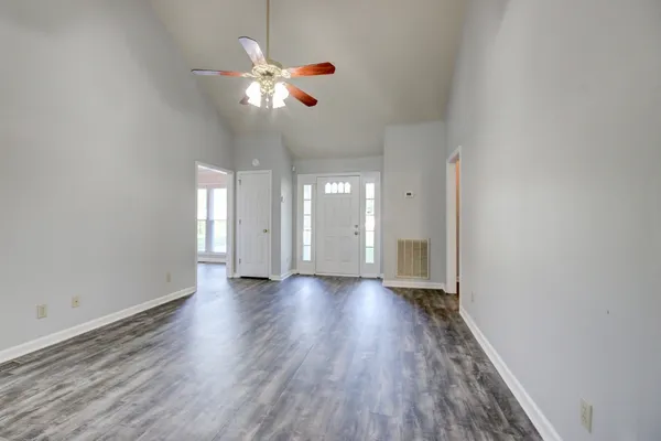 a view of an empty room with wooden floor and a window