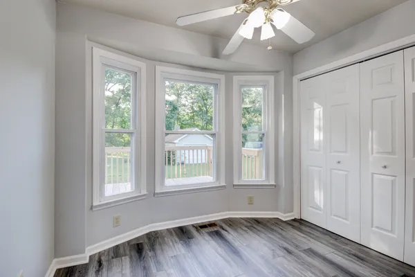 a view of an empty room with wooden floor and a window