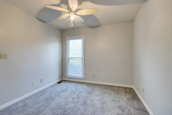 an empty room with a window and a fan