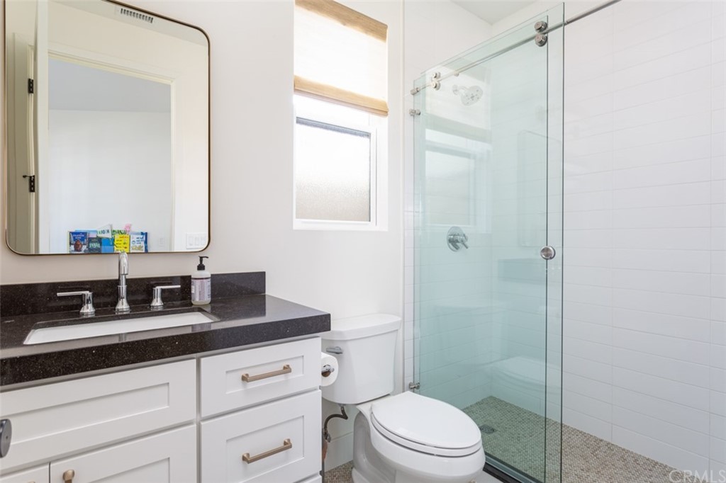 477 Magnolia Street Costa Mesa, CA 92627 - Photo 16 of 29 a bathroom with a granite countertop sink toilet a mirror a shower and a window