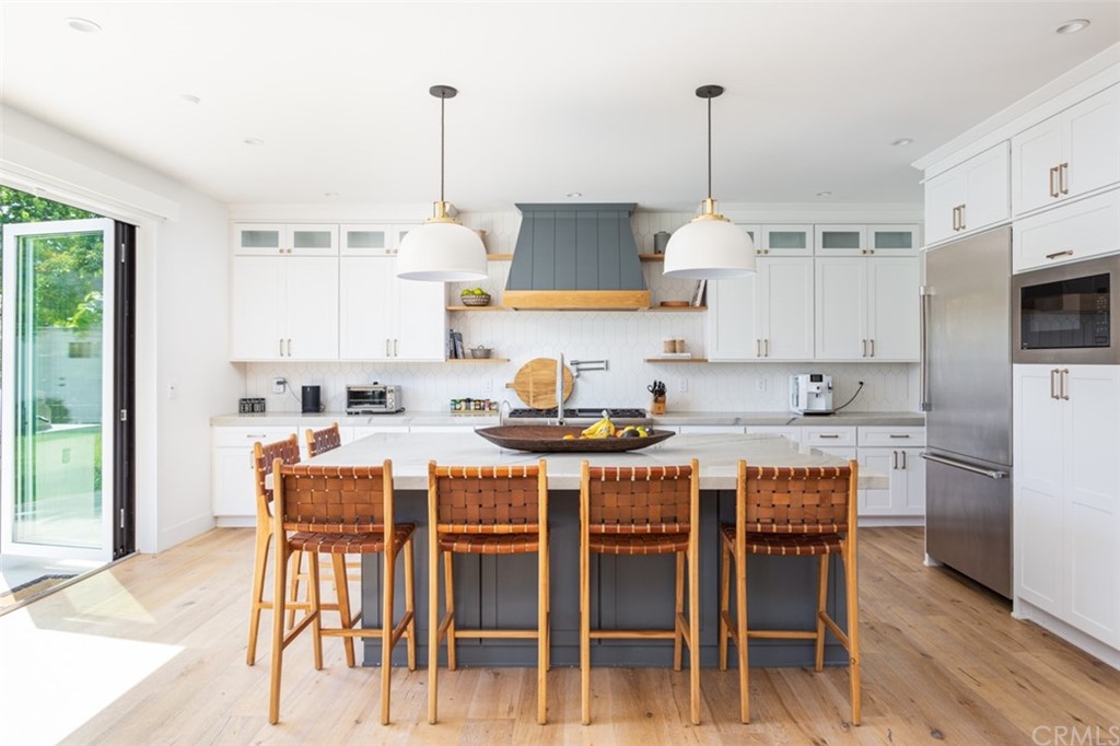 477 Magnolia Street Costa Mesa, CA 92627 - Photo 10 of 29 a kitchen with kitchen island a dining table chairs and white cabinets