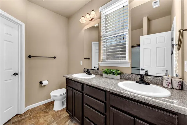 a bathroom with a granite countertop sink a toilet and a mirror