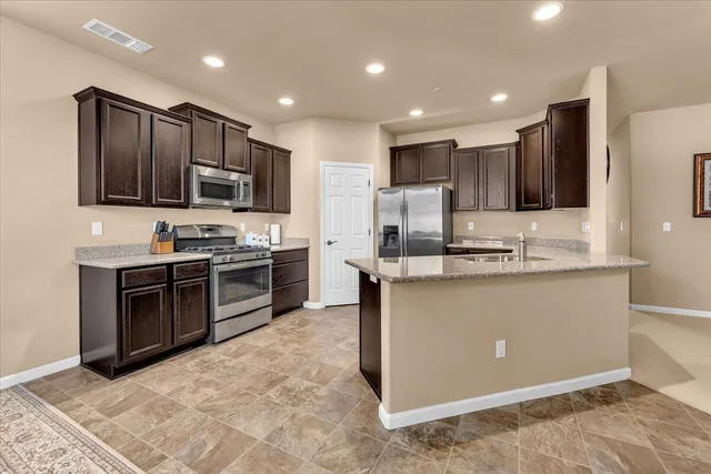 a kitchen with kitchen island granite countertop stainless steel appliances cabinets a sink and a counter top space