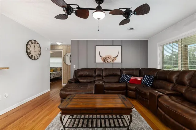a living room with furniture a ceiling fan and a large window